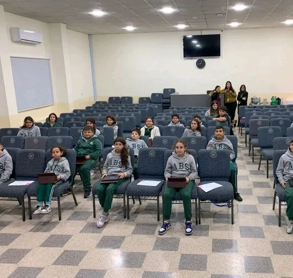 Students in a school hall holding tablets during a NEOMI session