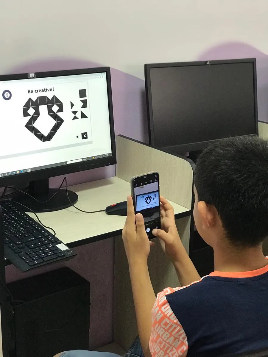 A student scanning a design on a screen with a phone